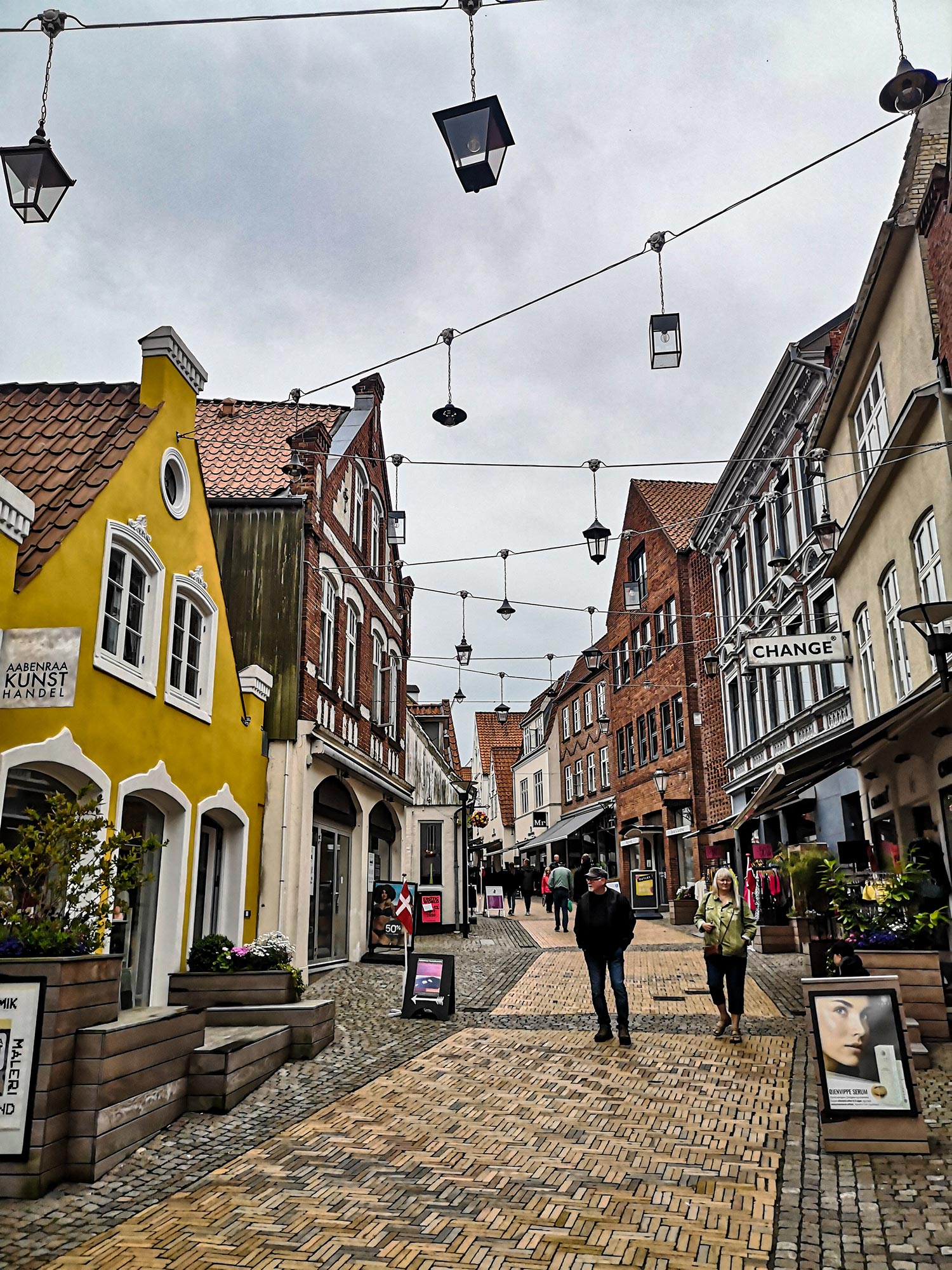Centre ville d'une ville au Danemark avec des piétons sur une route pavé.