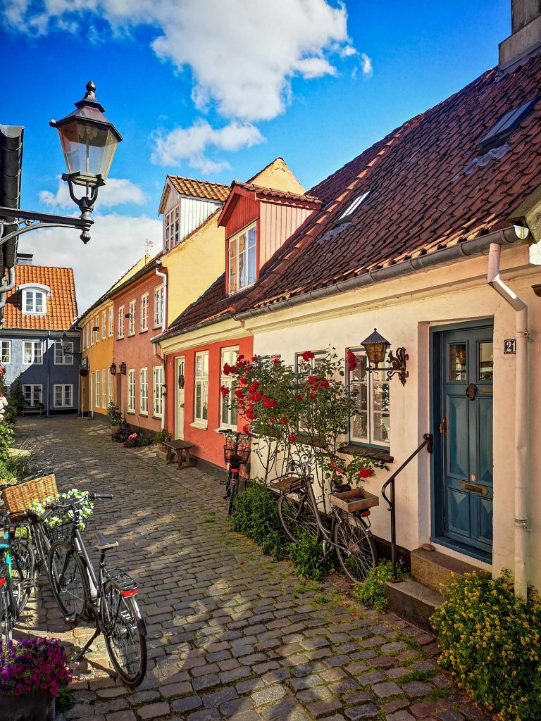 Habitations danoises avec des murs de couleurs différentes : rouge, jaune, rose, bleue et blanc. Les maisons sont sous un beau ciel bleau au Danemark