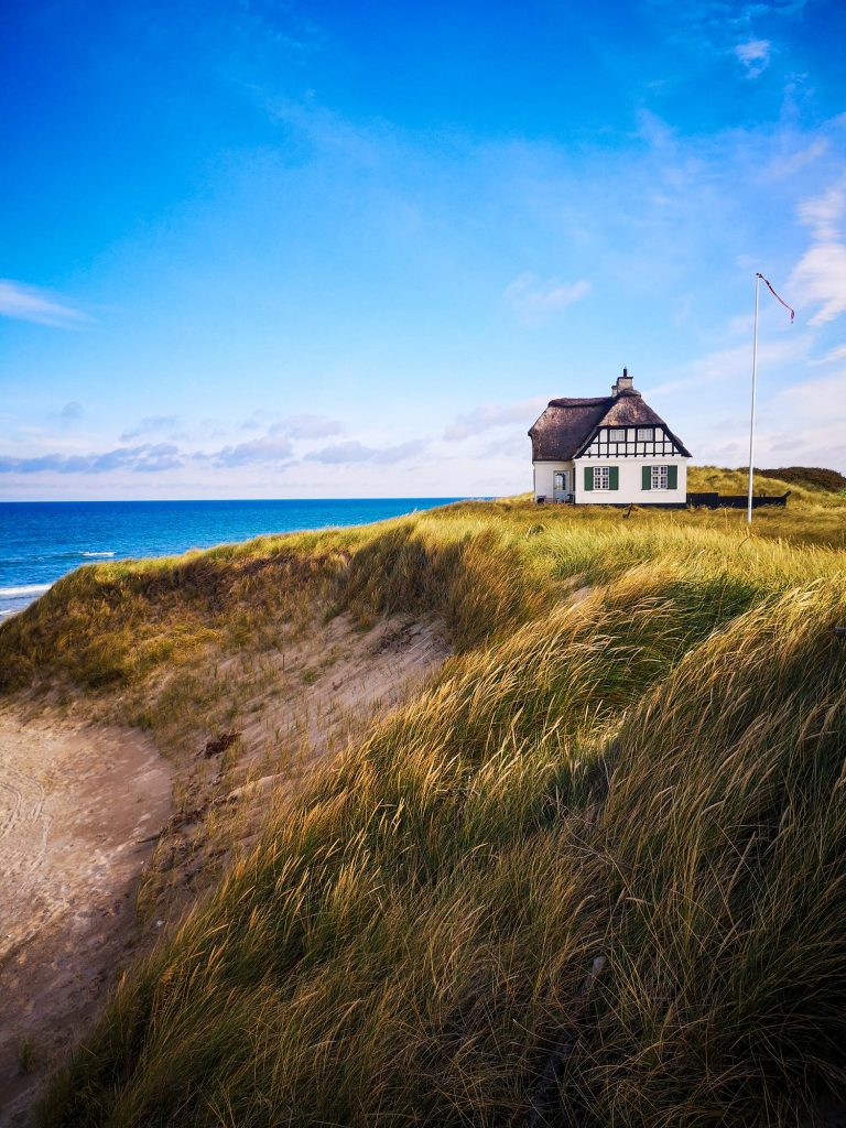 Maison au bord de la mer avec ces herbes prenant le vent à Lokken au Danemark