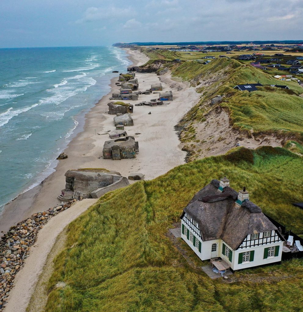 Une maison au bord de la mer et la plage avec des gros rochers avec l'horizon vaste. Paysage à Lokken au Danemark